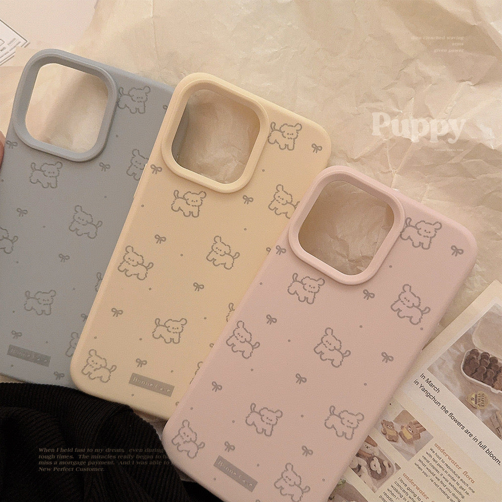 Pastel iPhone cases in pink and beige with a playful pattern of ribbons and dogs, offering stylish and protective coverage.